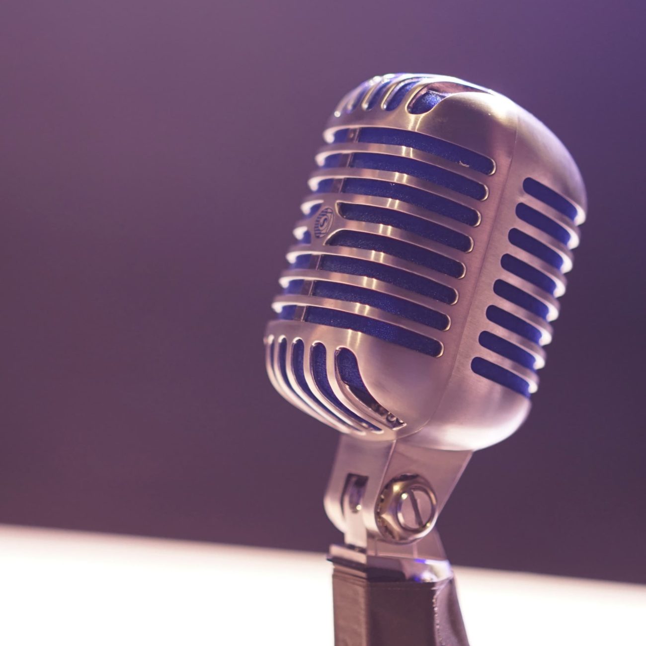 Close up of an old-fashioned radio microphone in front of a purple background.