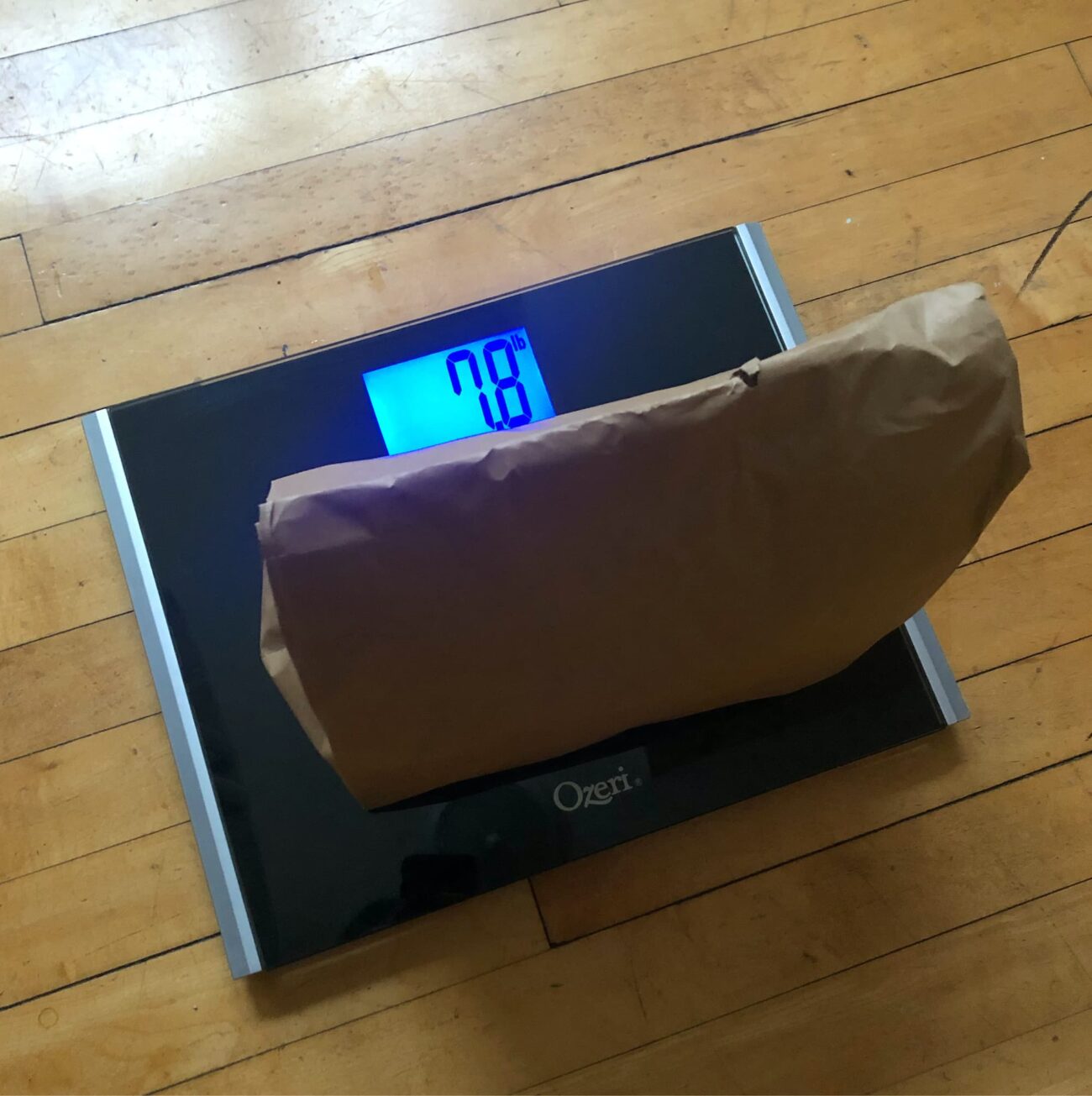 Half full brown paper bag sitting on bathroom scale. Scale reads 7.8lbs.
