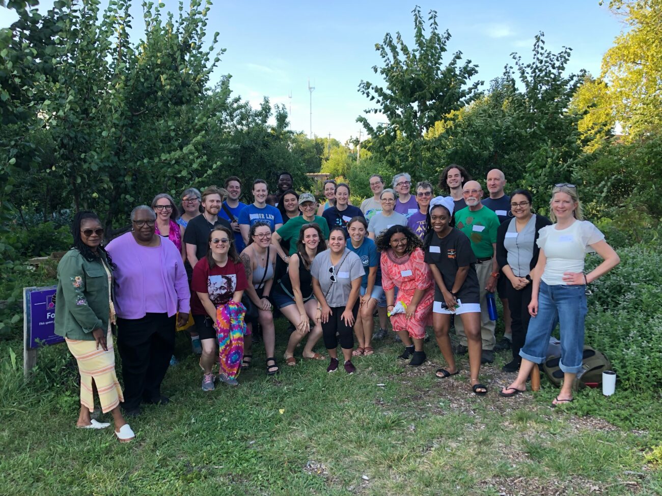 About 30 members of the Fair Future Movement standing in a group looking excited and happy in Victory Garden Initiative's urban farm.