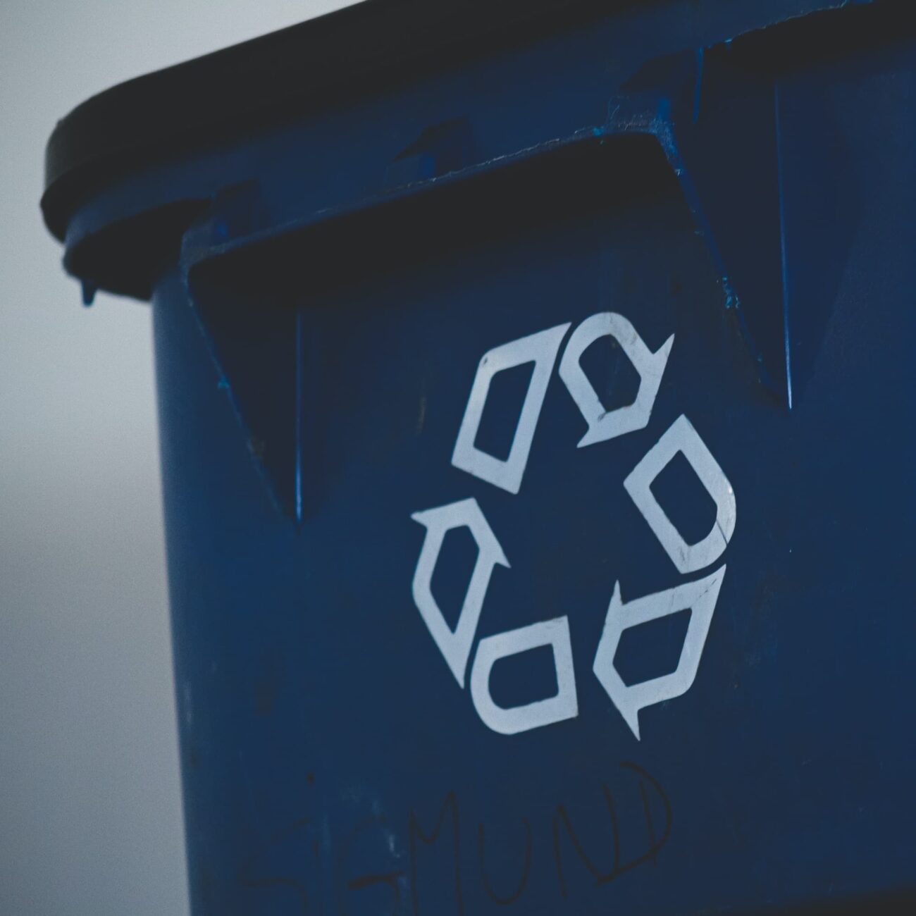 Close up of the recycle symbol on dark blue recycle bin.